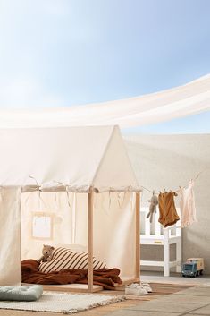 a white tent sitting on top of a wooden floor next to a bed covered in pillows