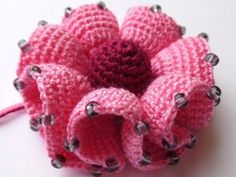 a crocheted pink flower with black dots on it sitting on a white surface