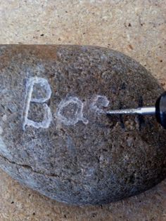 a rock with the word boo written on it and a screwdriver in its mouth