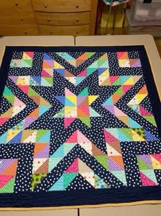 a quilted table topper sitting on top of a wooden dresser next to drawers