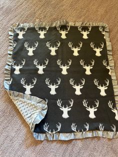 a black and white deer print blanket with ruffles on the bottom, laying on carpet