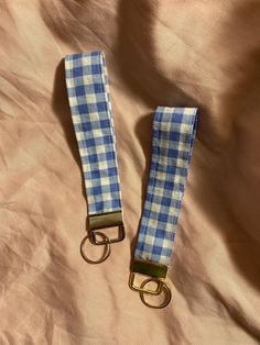 two blue and white checkered leashes laying on top of a tan cloth covered bed