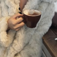 a woman in a fur coat holding a cup