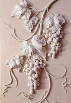 an intricately designed wall panel with grapes and vines on the bottom, in white