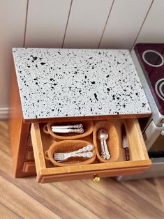 an open drawer with utensils and spoons in it