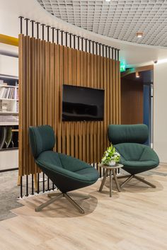 two chairs and a table in front of a wooden wall with a television on it