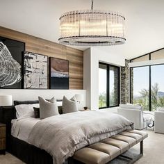 a large bed sitting in a bedroom under a chandelier next to two windows