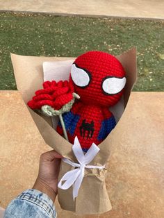 a hand holding a crocheted spider man bouquet