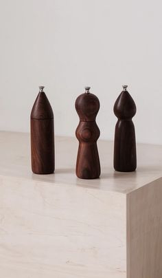 three wooden pepper shakers sitting on top of a white counter next to each other