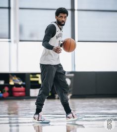 a man holding a basketball on top of a hard wood floor in an indoor gym