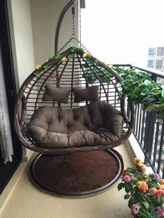 a hanging chair with cushions on the balcony