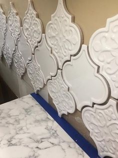 marble counter tops are lined up against the wall with decorative tiles on them, along with blue tape