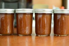 four jars filled with peanut butter sitting on top of a wooden table