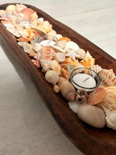 a wooden boat filled with seashells and a candle