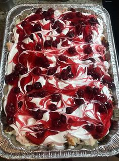 a cake with cherries and whipped cream on it sitting in a tin foil pan