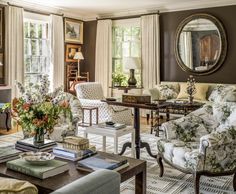 a living room filled with lots of furniture next to a window covered in white curtains