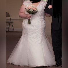 a man and woman standing next to each other in front of a mirror holding flowers