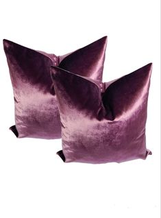 two purple velvet pillows sitting next to each other