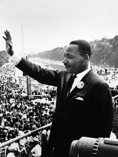 a man in a suit and tie waves to the crowd