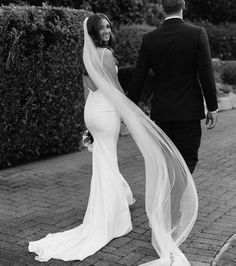 the bride and groom are walking down the sidewalk together, holding hands with each other