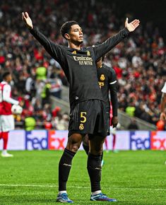 a man standing on top of a soccer field holding his arms up in the air