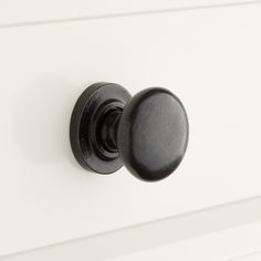 a black knob on a white cabinet door