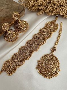 two pieces of jewelry sitting on top of a white cloth covered table next to a wooden block