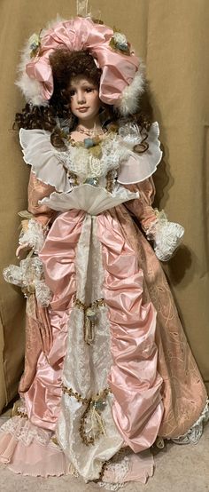 a doll is sitting on the floor wearing a pink dress and bonnet with white lace