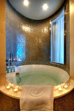 a bathroom with a large jacuzzi tub next to a window and candles on the counter