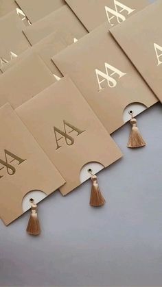 six business cards with tassels on top of each one and the letter a in gold foil