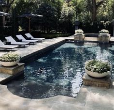 an outdoor swimming pool with lounge chairs and umbrellas