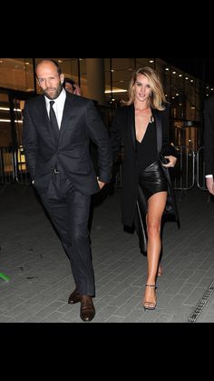 a man in a suit and tie walking next to a woman in a black dress