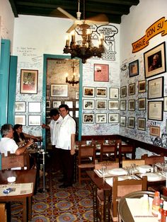 people sitting at tables in a restaurant with pictures on the walls