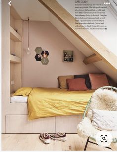 an attic bedroom with yellow bedding and wooden flooring is featured in the magazine