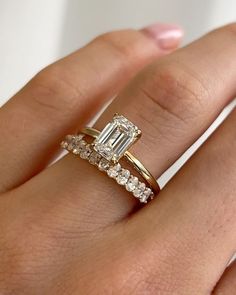 a woman's hand with a diamond ring on top of her finger and the engagement band