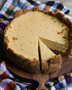 a cheesecake on a wooden board with a piece cut out and ready to be eaten