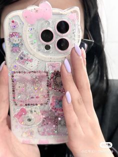 a woman holding up her phone case with hello kitty on the front and pink glitters on