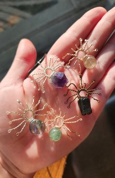 a person's hand holding several different types of beads and wire tree ornaments in their palm