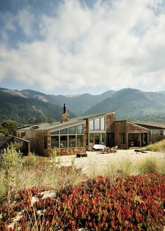 a house in the middle of a field with mountains in the background