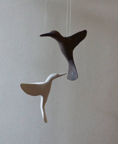 two ceramic birds hanging from strings on a wall