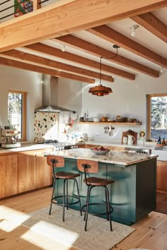 a kitchen with two stools in front of an island and stove top oven on the other side