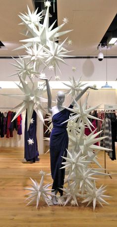 a woman standing in front of a display of white snowflakes on a wooden floor