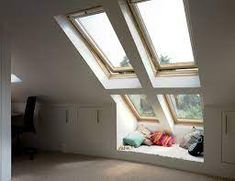 an attic bedroom with two skylights and no curtains on the windows sill,