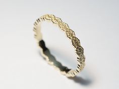 a gold wedding band with intricate designs on the outside and inside, sitting on a white surface