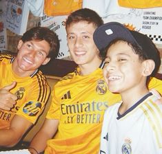 two boys and an older man are posing for a photo in their soccer uniforms,