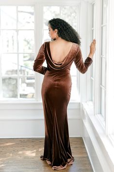 a woman in a brown dress looking out the window