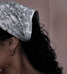 a close up of a woman wearing a head scarf and earrings with her hair pulled back