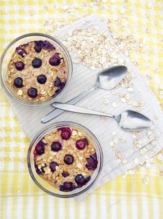 two bowls filled with oatmeal and blueberries on top of a table