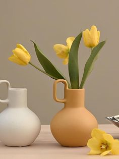 three vases with yellow flowers in them on a table