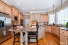 a large kitchen with an island and stainless steel refrigerator freezer next to it's center island